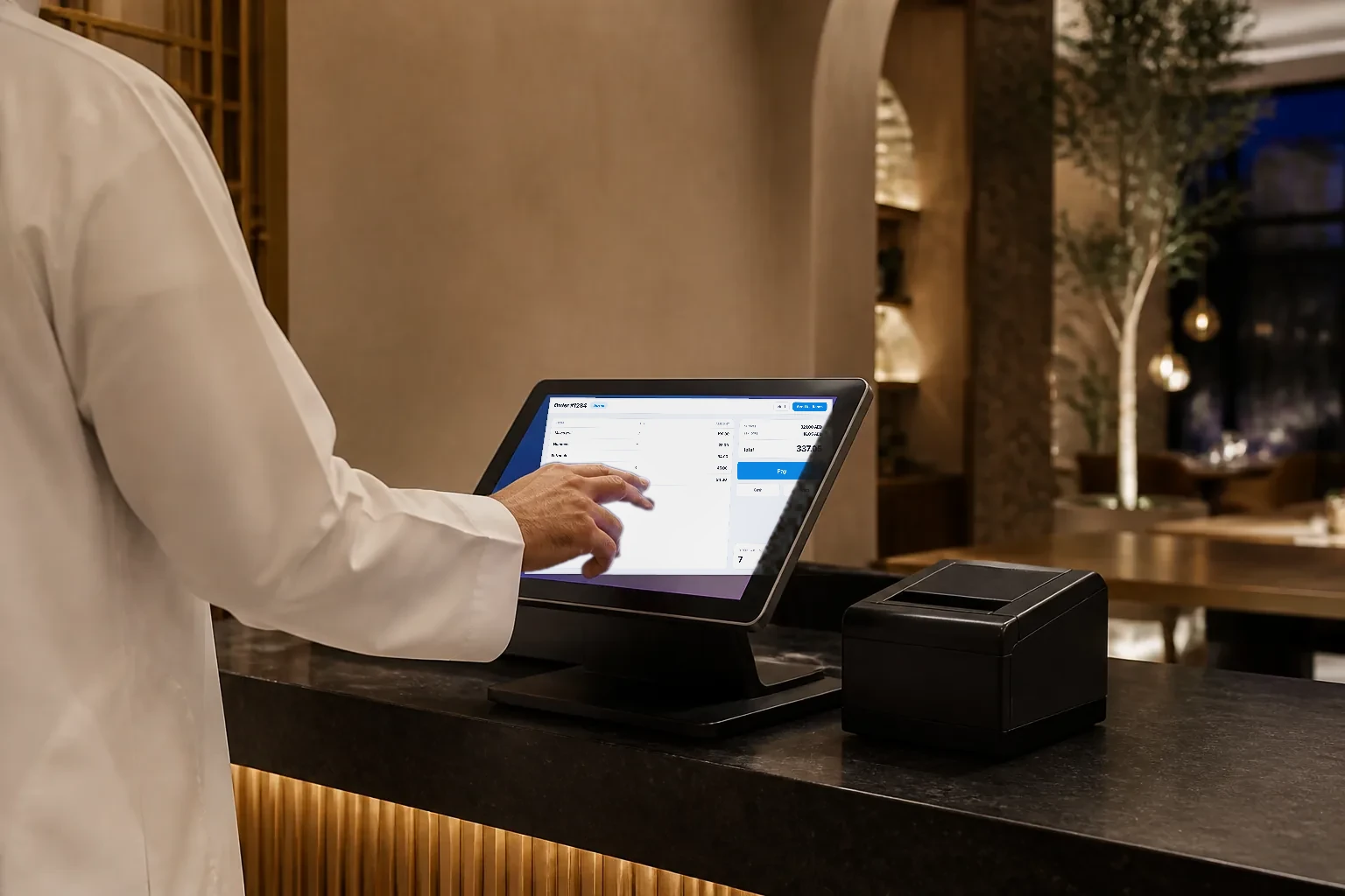 A staff member using a point of sale terminal at the counter of an elegant Gulf restaurant.